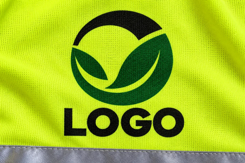 Wizualizacja sublimacji: czarno-zielone logo, widoczny splot i żółty kolor materiału